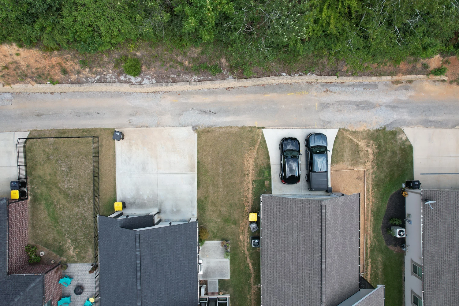 Overhead view shows neighboring driveways and narrow lawns, highlighting how each yard flows from the homes to the roadside