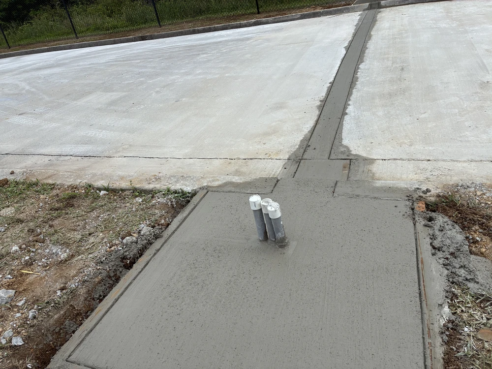 Ooltewah, TN concrete slab shows a crisp drain channel and capped pipes carrying water across the bright finished surface