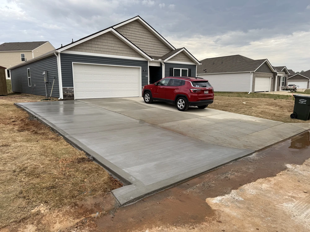 New concrete driveway extension in front of a dark gray garage with a red SUV at a Ringgold GA home.